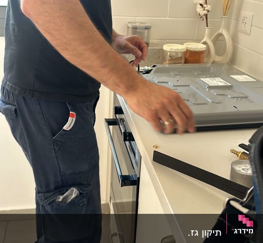 אדם עובד על מכשיר במטבח עם כלים על השיש